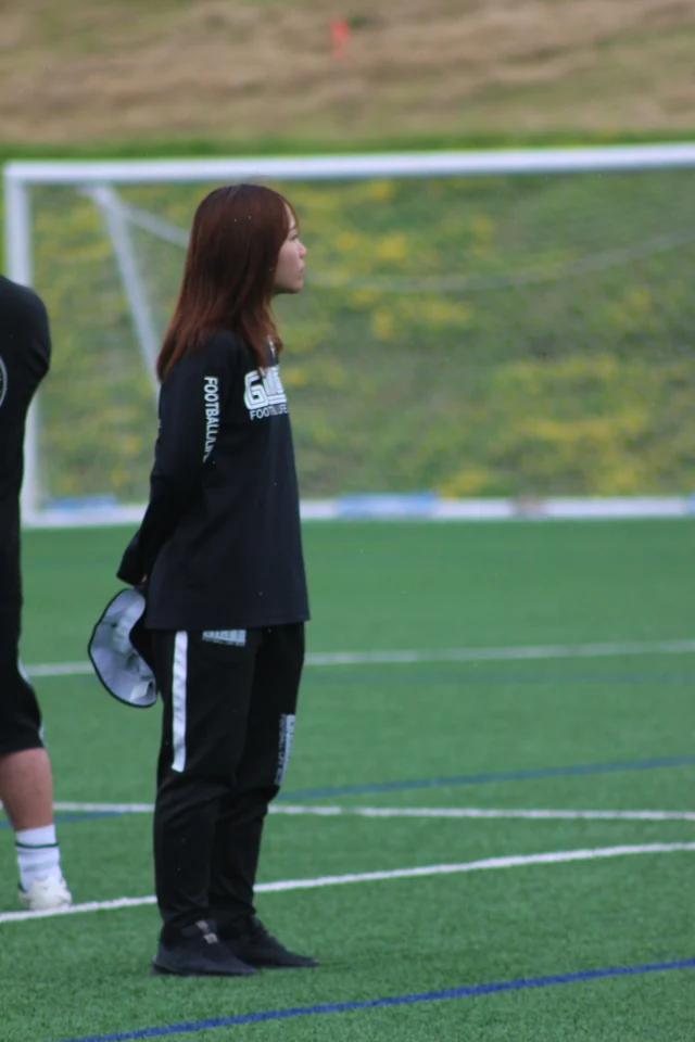 ピッチで活動を見守る真栄FCの女性コーチ
